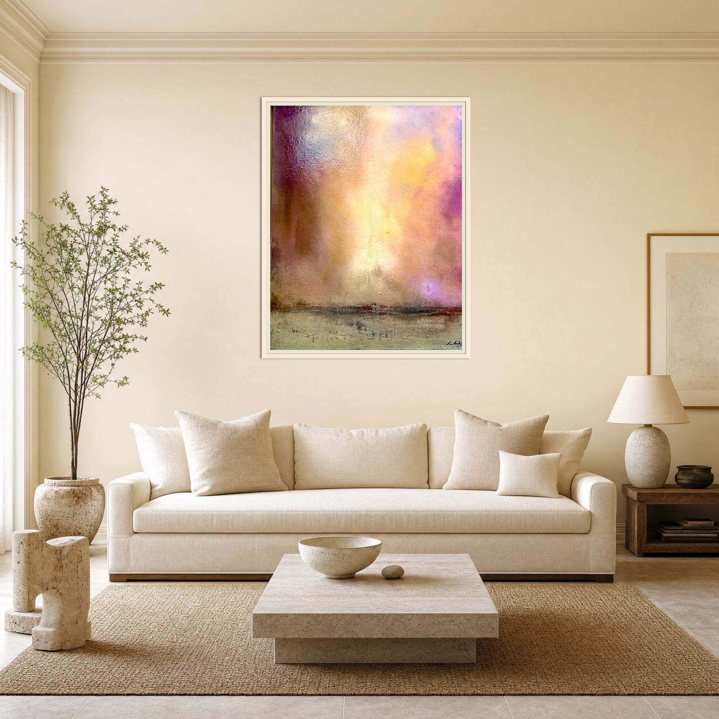 A framed abstract landscape art print with soft purple, yellow, and orange tones hangs on a beige wall above a modern white sofa in a styled living room.