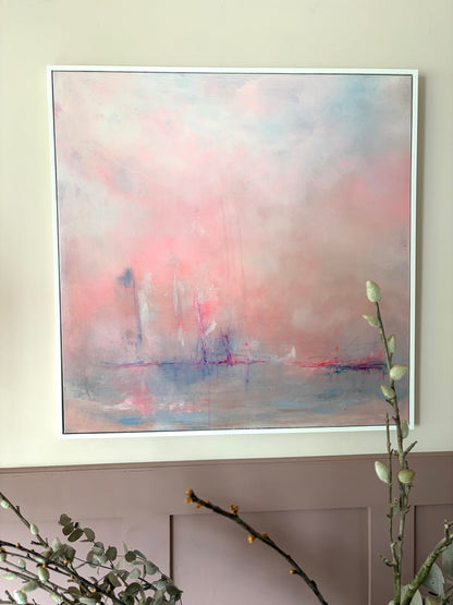 Framed abstract painting with soft pink and blue hues on a wall.