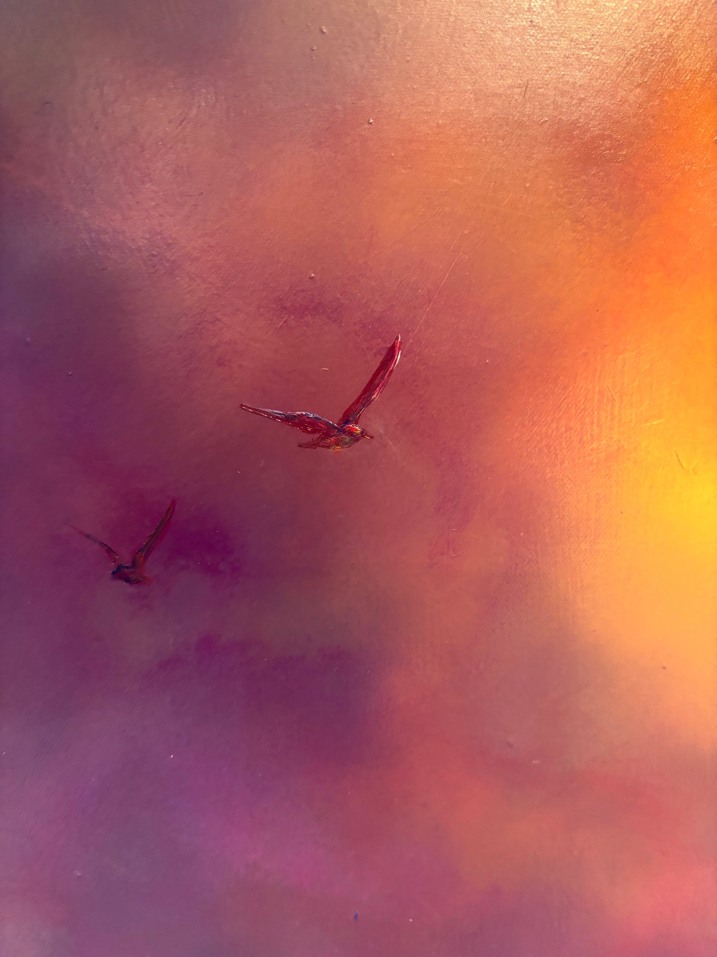 Two birds flying against a colorful, abstract background with warm tones.