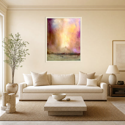 A framed abstract landscape art print with soft purple, yellow, and orange tones hangs on a beige wall above a modern white sofa in a styled living room.